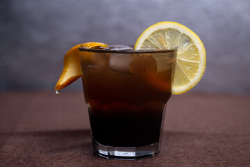 alcoholic drink with Cola and a slice of lemon in a glass
