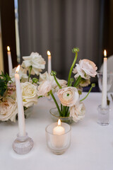 Banquet table decorated with plates, cutlery, candles, glasses and flower arrangements