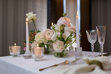 Banquet table decorated with plates, cutlery, candles, glasses and flower arrangements