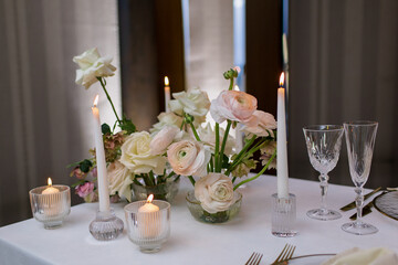 Banquet table decorated with plates, cutlery, candles, glasses and flower arrangements