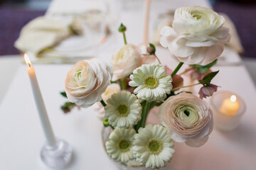 Banquet table decorated with plates, cutlery, candles, glasses and flower arrangements