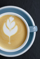 Cup of fresh cappuccino coffee in flat lay. Aromatic Italian hot drink shot directly from above on table