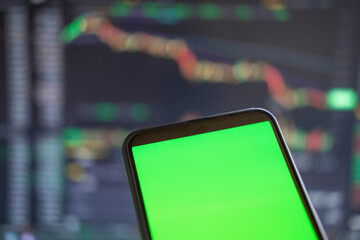 Black phone with blank mockup screen on rising stock graph. Closeup hand showing smartphone isolated green display, Online banking, Fund App use. Financial analyst on Invest Market. Bank collapse 2023