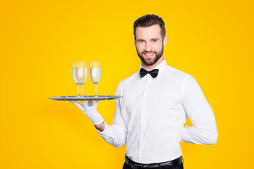 Portrait of cheerful friendly man in classic white shirt and black bow holding hand behind the back...