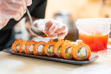professional chef's hands making sushi roll in a restaurant kitchen