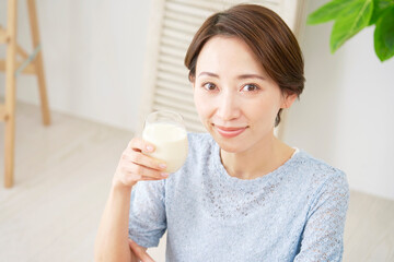 家で豆乳を飲む女性　カメラ目線