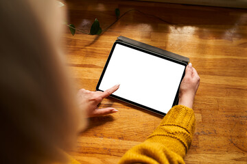 Mockup of woman using digital tablet with blank white screen on kitchen counter