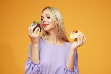 Beautiful blonde girl in a lilac dress with cakes on a yellow background. Studio. Diet and health