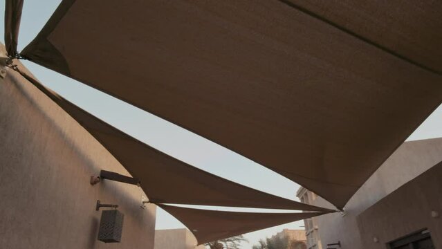 POV of walking in ancient eastern arabic city with old buildings. White canopy overhead at the street.