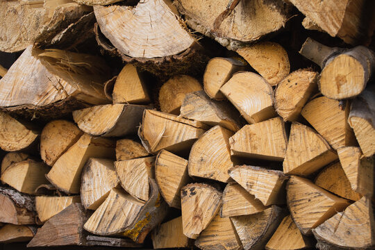 A stack of dry wood for a fireplace and a fire in the backyard - a supply of solid fuel for heating