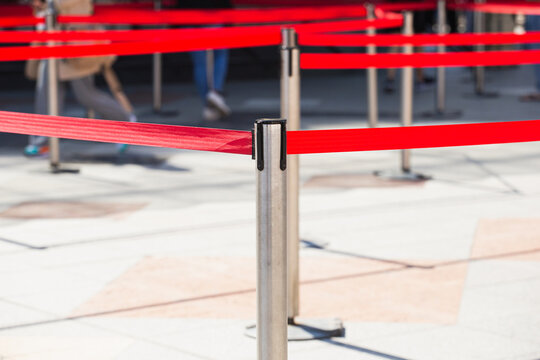 Red restrictive belts on metal posts for temporary fencing and control - organization of people movement