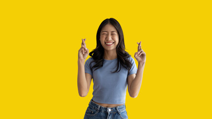 Young Asian woman making a symbolic gesture with fingers crossed showing good luck, White lie...