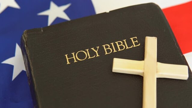 Old Holy Bible with a cross on flag of USA. Slow motion.