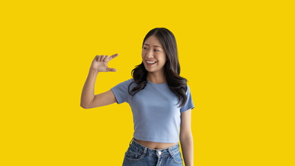 Asian woman with holding copyspace imaginary on the palm to insert an ad, Showing copyspace pointing, Showing her hand to present something on yellow background.