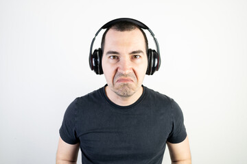 young man male guy model wearing headphones cool fashion style looks unhappy angry stand wear bad music sound listening