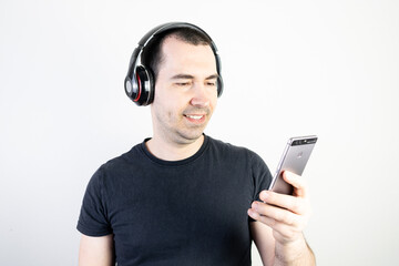 young man male guy model wearing headphones cool fashion style looks happy stand wear enjoy music good sound listening relax smile hold smartphone