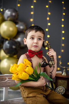 A little boy at an old telephone with yellow flowers is waiting for a call