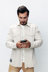 Close-up portrait man holding a phone smile typing a message, chatting online freelance work on a white isolated background, fashionable clothing style, copy space, space for text