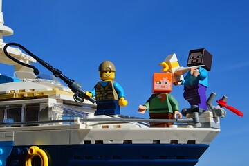 Fototapeta premium LEGO Minecraft Steve and Alex on yacht with a boy with fishing pole from LEGO Creator series, enjoying sunny day on sea. Steve just captured a LEGO Seagull.