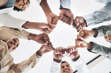 Obraz premium Team building, circle or happy business people fist bump for motivation in office meeting together. Diversity, low angle or employees with mission, strategy or group support for project goal