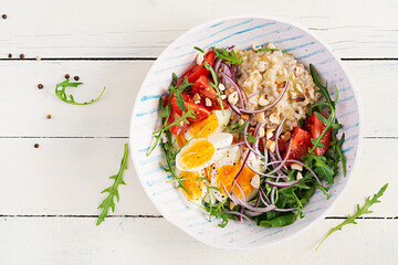Breakfast oatmeal porridge with boiled eggs, tomatoes and red onions. Healthy balanced food. Trendy food. Top view, flat lay