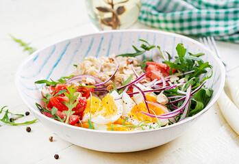 Breakfast oatmeal porridge with boiled eggs, tomatoes and red onions. Healthy balanced food. Trendy food.