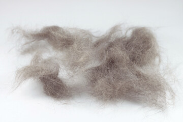 A lump of cat hair and a comb for combing hair. White isolated background. Pet care.