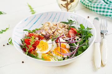 Breakfast oatmeal porridge with boiled eggs, tomatoes and red onions. Healthy balanced food. Trendy food.