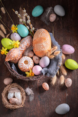 Festive Easter basket with painted eggs, bread and flowers.