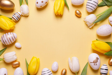 Frame of painted Easter eggs and tulip flowers on yellow background, flat lay. Space for text