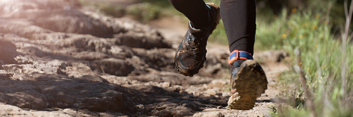 Trail running athlete exercising for fitness and health outdoors on mountain pathway, closeup of running shoes in action