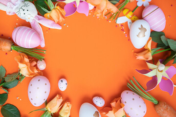 easter frame with fresh spring carrots ,easter eggs,confetti,decor on an orange background. top view. copy space. flat lay.