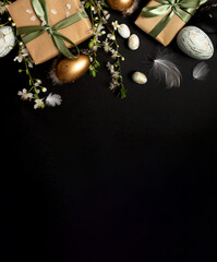 stylish dark easter layout with eco-wrapped gifts, golden and marble eggs, cherry blossoms on a black background. top view. copy space. flat lay. place for text