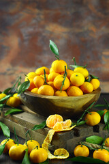 Mandarin orange on rustic wooden bowl and dark wooden background. 