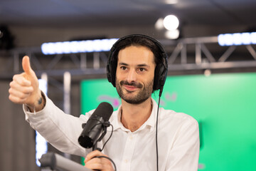 jeune présentateur qui anime une émission de radio ou de télévision dans un studio. Il porte un casque et tient un micro dans ses mains