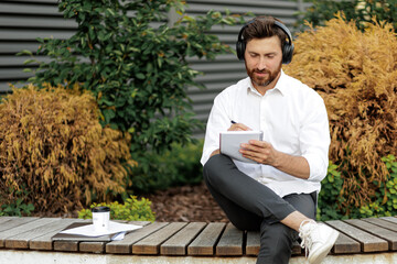 Manager noting thoughts in diary while sitting on bench