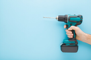 Young adult man hand holding and showing dark black green professional battery driver drill on...
