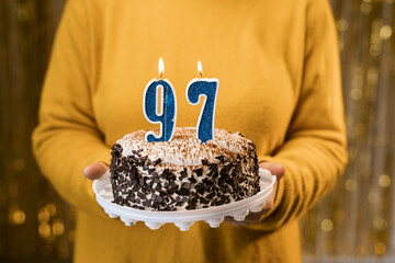 Happy birthday. Woman holding fresh delicious birthday cake with burning candle number 97, close...