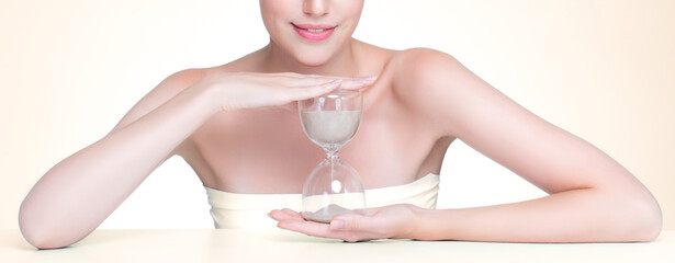 Closeup personable model holding hourglass in beauty concept of anti-aging skincare treatment....