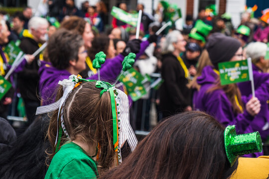Girl with green clover headband, green outfit, crowd in green hats in background, watching the parade march in Dublin city center, Saint Patricks day, Ireland