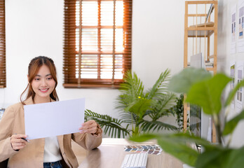 Professional interior designer working in the office, Portrait of young asian female architect working on business of Real estateproject , considering on a house plan choosing swatches and material..