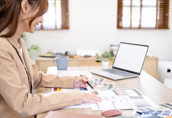 Professional interior designer working in the office, Portrait of young asian female architect working on business of Real estateproject , sketching on a house plan choosing swatches and material..