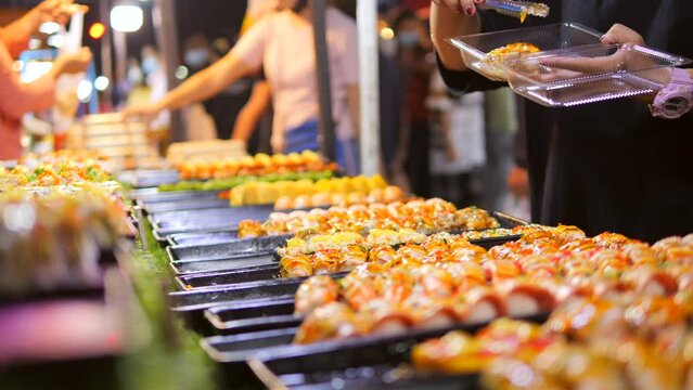 Local Asian Street Food: Woman Choosing Traditional Japanese Sushi and Rolls at Night Market. High Quality 4K Slow Motion Cinematic Foodie Concept Footage. Bangkok, Thailand.