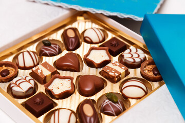 Close up of open small gift box of Swiss chocolate candies. Luxurious selection of milk, dark and white miniature masterpieces