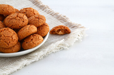 Traditional Italian almond cookies amaretti in a white plate on a white background.Famous amarettini cookie biscuits.Delicious Christmas pastry. Selective focus.