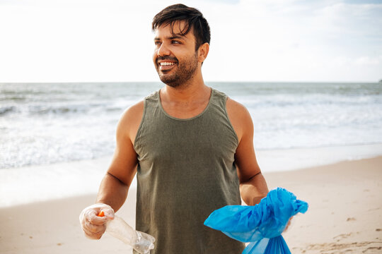 Portrait of proud volunteer man collecting trash on the beach. Ecology concept