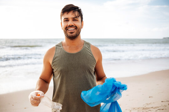 Portrait of proud volunteer man collecting trash on the beach. Ecology concept