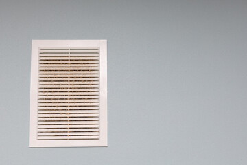 wall-mounted plastic ventilation grate clogged with dust