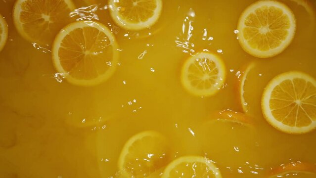 Super Slow Motion Shot of Fresh Orange Slice Splashing to Orange Juice