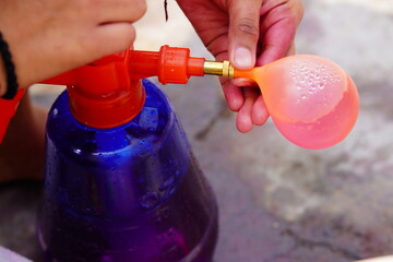 Naklejka premium someone filling water in the balloon for holi